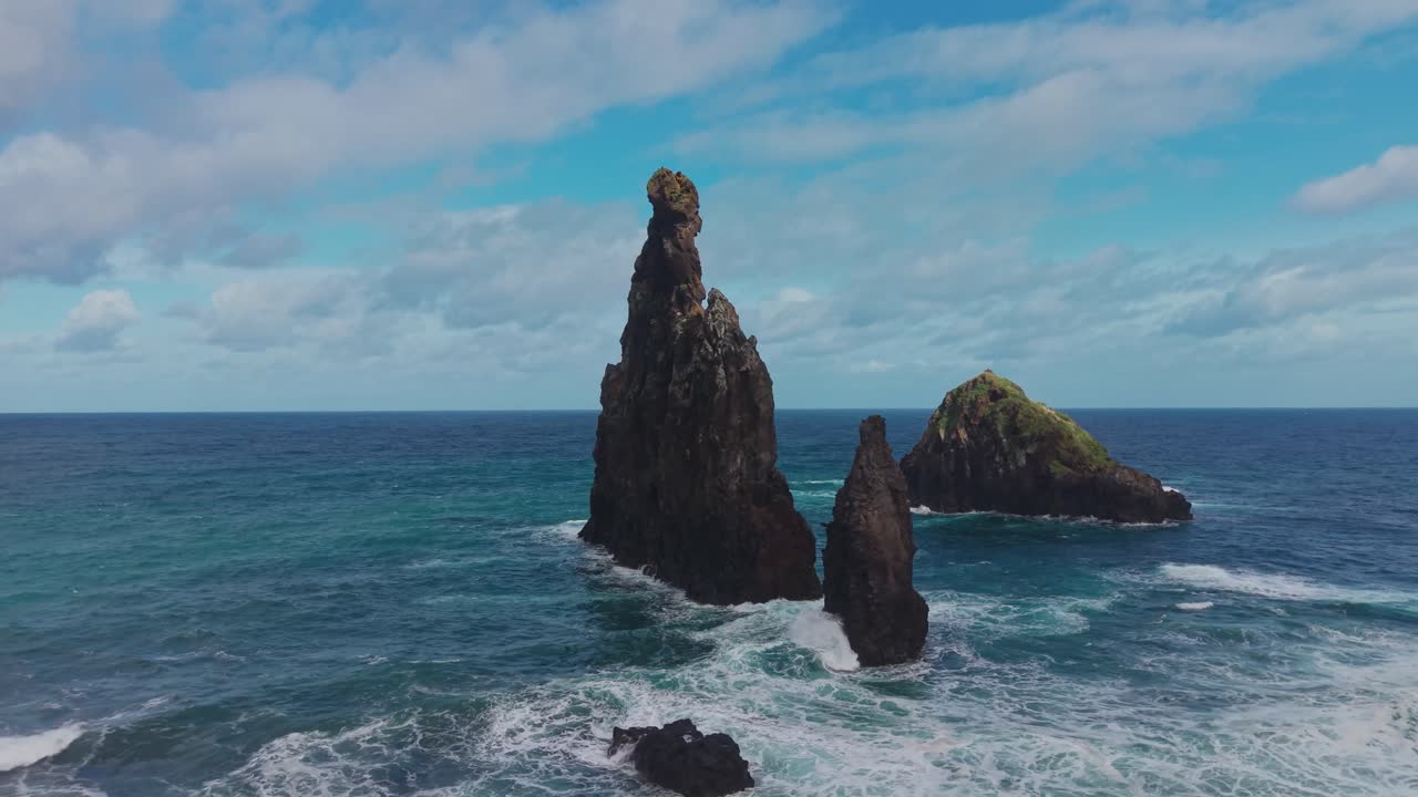 Veduta aerea di drammatici faraglioni a Ribeira da Janela a Madeira, con onde atlantiche che si infrangono su formazioni rocciose vulcaniche e montagne nebbiose sullo sfondo