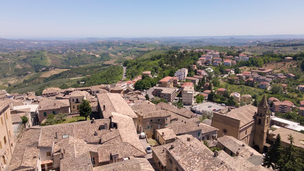 toma de drones de un antiguo pueblo medieval durante una soleada tarde de verano con autos conduciendo y una amplia vista del valle a lo lejos ubicado en penne, abruzzo, italia