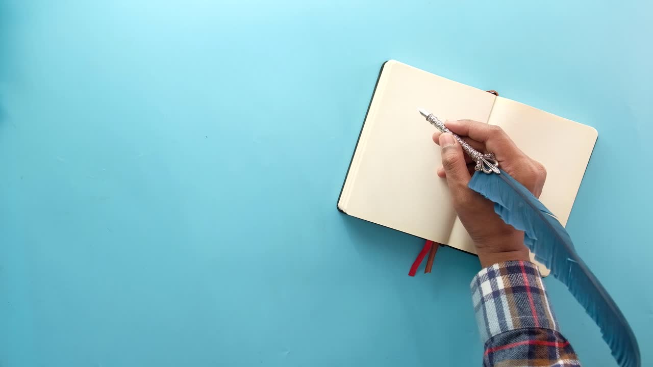 Hand Writing in a Notebook with a Feather Pen