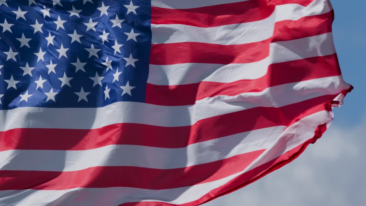 United States flag rippling in strong wind, daylight, close-up, natural outdoor lighting, dynamic movement