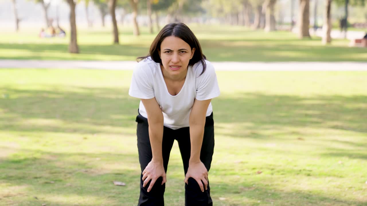 mujer tomando respiraciones largas después de un entrenamiento en un parque por la mañana