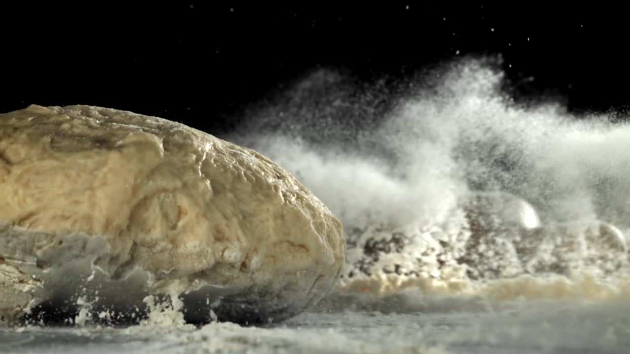 Fresh Dough Ball Falling onto Floured Surface in Slow Motion