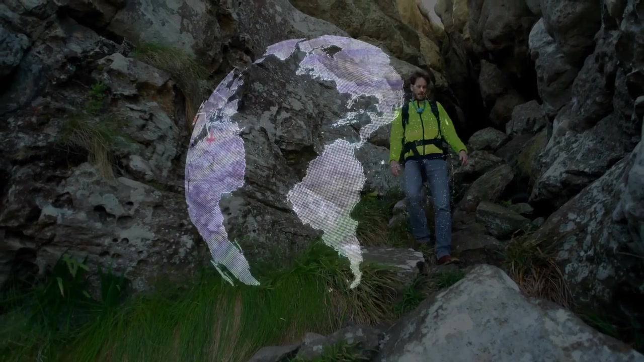 Hiker stepping through boulders initiating rotating globe showing travel icons navigating canyon