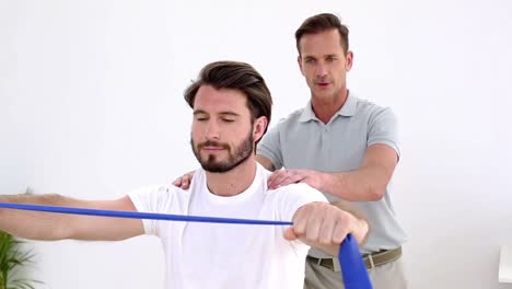 physiotherapist checking patient pulling a resistance band shoulders