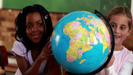 Cute-pupils-smiling-around-a-globe-in-classroom