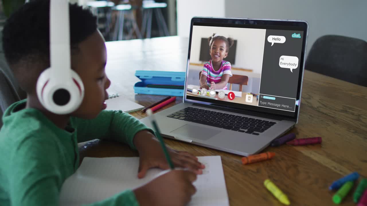 Schoolboy using laptop for online lesson at home, with school friend and web chat on screen