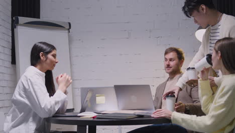 Young-Man-Bringing-Takeaway-Coffee-To-His-Happy-Colleagues-During-A-Team-Meeting-1