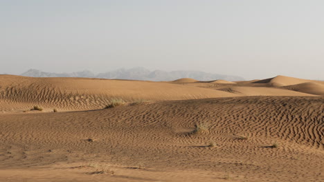 Paisaje-Desértico-Del-Medio-Oriente-Cerca-De-Dubai-En-Los-Emiratos-árabes-Unidos-Con-Dunas-De-Arena-Y-Montañas-Distantes