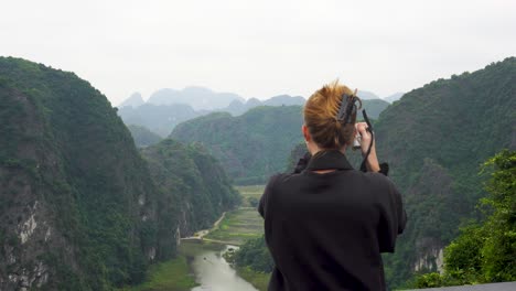 view of behind female tourist taking photo from hang mua viewpoint in vietnam