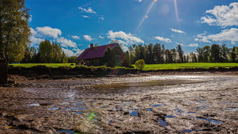 timelapse of a countryside lake being drained by man on a sunny day in latvia with a wooden house on the background