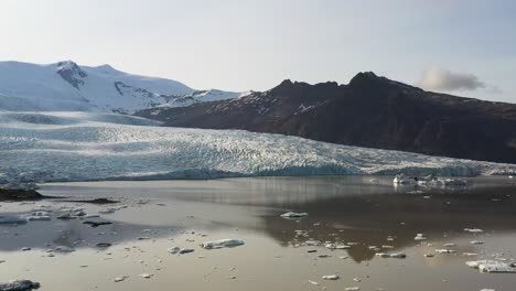 Vast-Vatnajökull-glacier-in-Iceland-with-glistening-ice-and-snow-under-a-clear-blue-sky,-mirrored-in-a-calm-glacial-lake