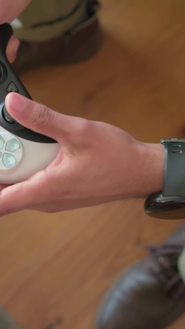 Vertical video: Gaming, man picking up controller and moving stick at home with watch, green pants
