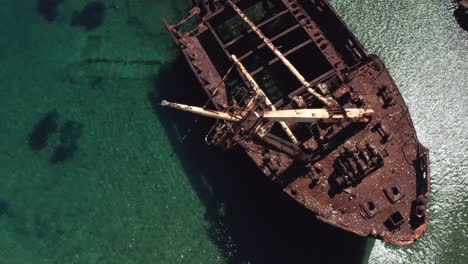 wide angle drone shot to close-up of the bow of the abandoned boat in liverio bay near kalotaritissa village, cyclades islands, greece