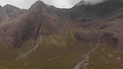 Drone-panoramic-right-movement-shot-of-fairy-pools-landscape-with-green-grass,-river-and-tall-mountains-in-the-background