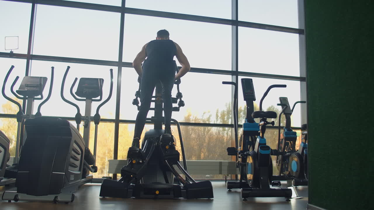 체육관에서 립틱 트레이너에서 운동을 하는 아름다운 스포츠 긍정적 인 젊은 남자.