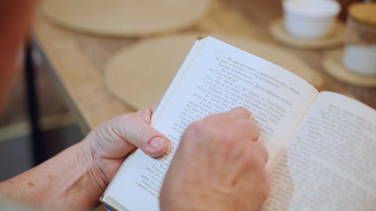Caucasian grandma evening braille reading with tea hands turn pages near lamp saucer on table gentle ritual before rest warm cozy atmosphere slow patient routine comfort and tradition