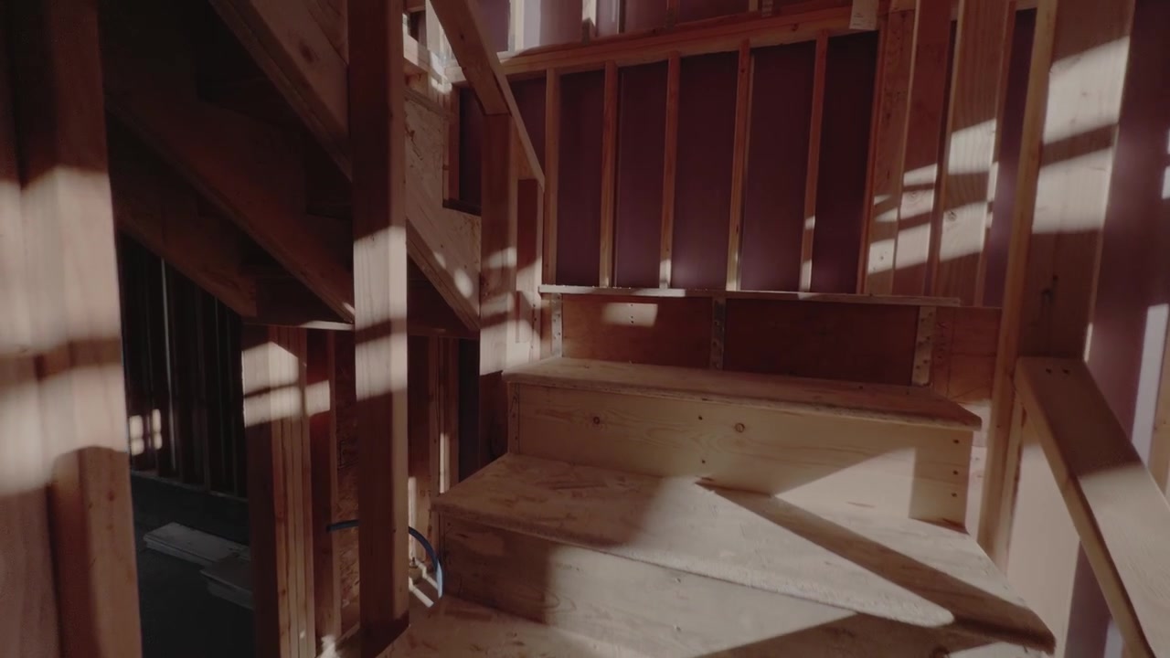 Glissement doux vers le haut le long d'escaliers en bois à l'intérieur d'une ossature de maison inachevée.