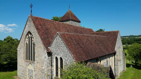 A-rising-boom-shot-of-St-Lawrence-the-Martyr-church-in-Godmersham,-rising-above-a-tree