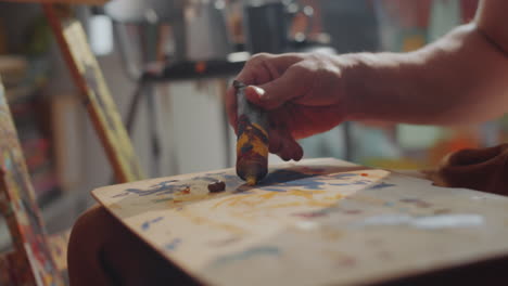 artista masculino vertiendo pintura en una paleta de madera