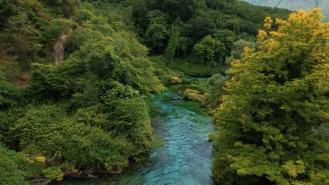 turquoise water of syri i kaltër, albania’s blue eye, seen from above in a peaceful forest setting