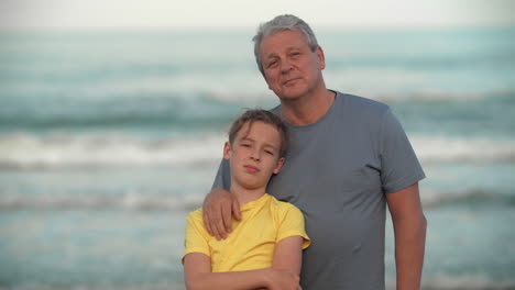 abuelo con un nieto adolescente junto al océano