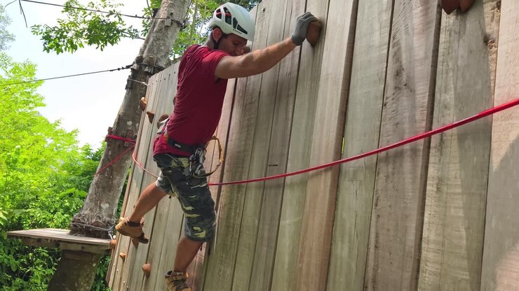 Person Climbing Wooden Wall at Adventure Park