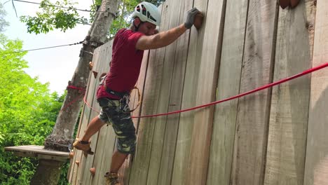 person climbing wooden wall at adventure park