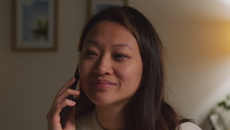 Close-Up-Of-Woman-Spending-Evening-At-Home-Walking-Around-Lounge-Talking-On-Mobile-Phone