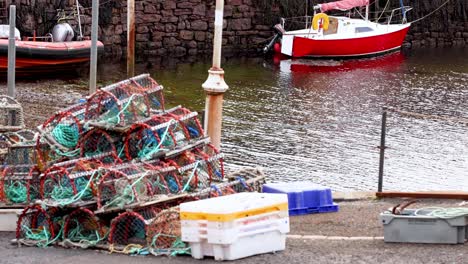 barco rojo cerca de redes y cajas de pesca