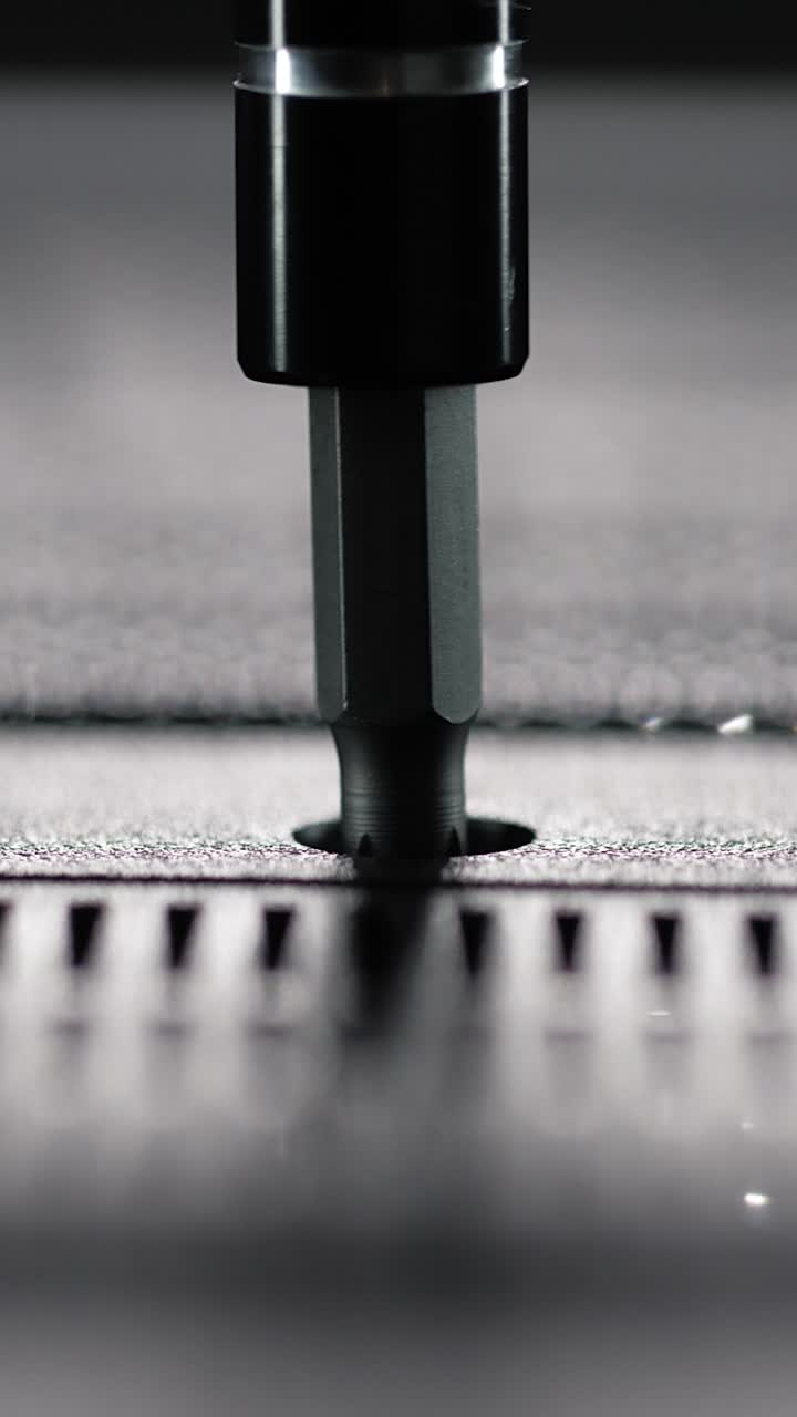 Macro view of driver bit tightening a single screw into perforated panel of an electronic device