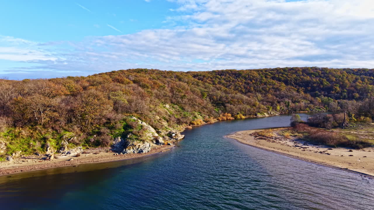 Serene river flowing between vibrant hills and gentle waves during a calm autumn afternoon