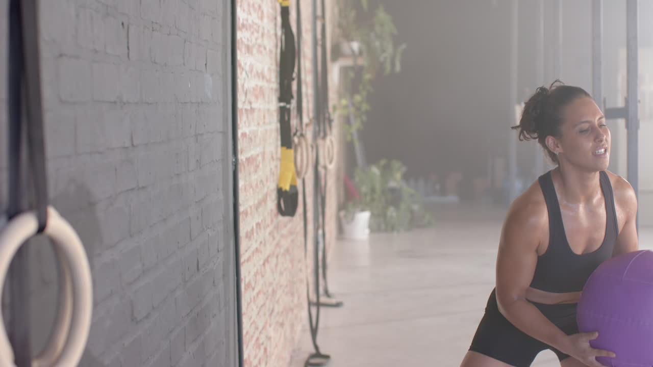 Lifting exercise ball, woman working out in gym, focusing on fitness training, copy space