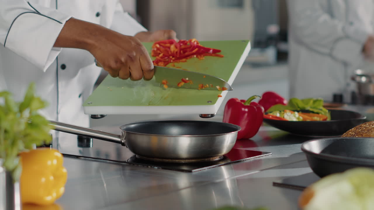 Male chef preparing chopped bell pepper in restaurant kitchen