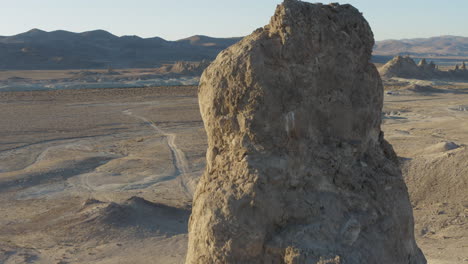 A-close-descending-aerial-shot-of-a-large-pinnacle-in-the-california-desert-at-sunrise