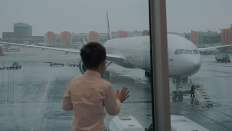 child looking at the airplane through the window