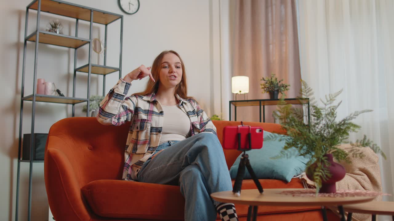 소녀 블로거 인플루언서가 스마트폰으로 셀카를 찍고, 집에서 온라인으로 가상 소셜 미디어 비디오를 만 ⁇ 니다.