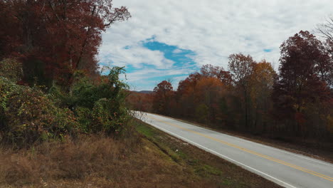 asphalt road between autumn trees in ar, usa - drone shot