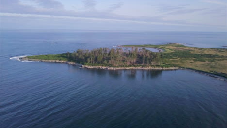 Aerial-shot-flying-above-blue-Atlantic-Ocean-waves-crashing-against-Richmond-Island-off-the-Maine-coast