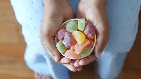 woman's hands holding a bowl of colorful fruit-shaped jellies