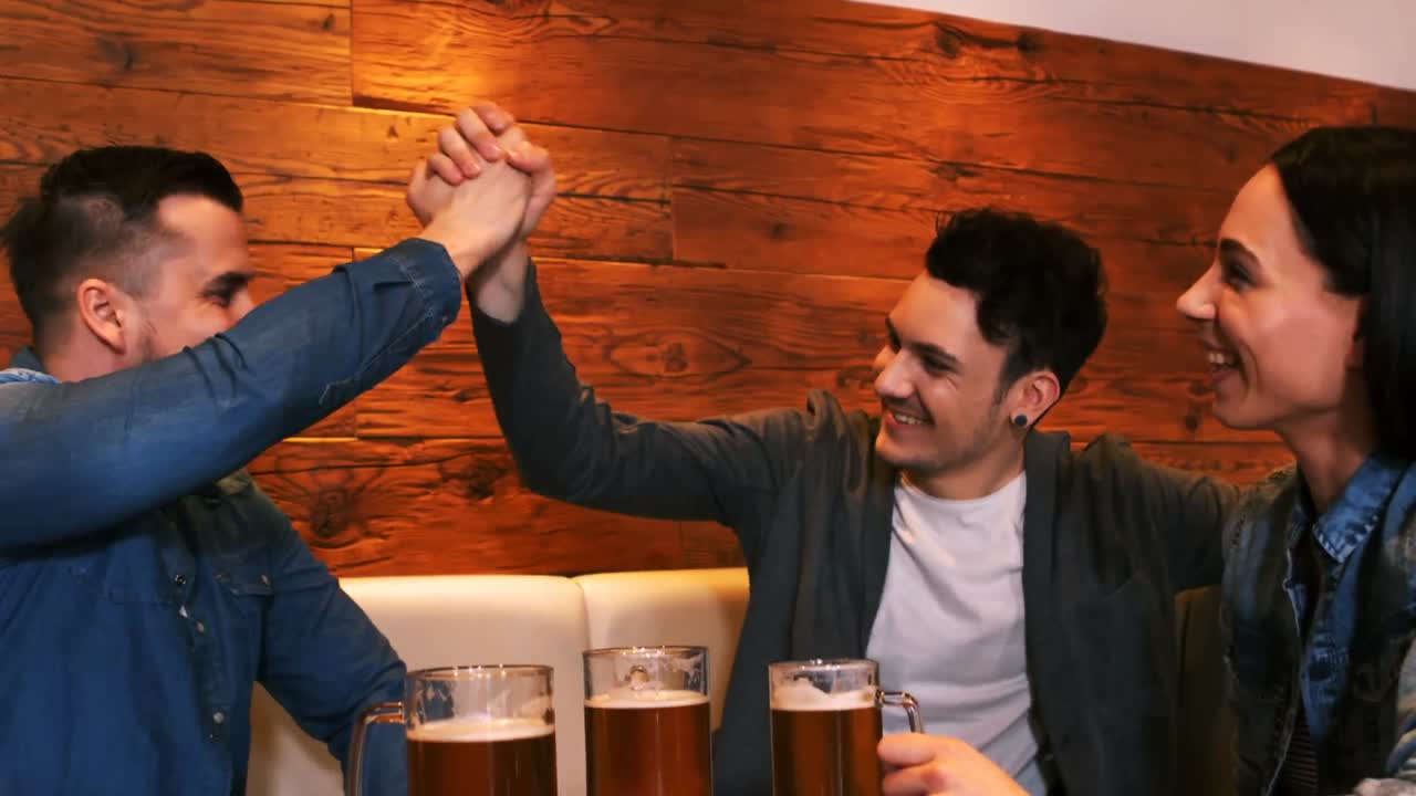 amigos felices dando los cinco mientras toman un vaso de cerveza