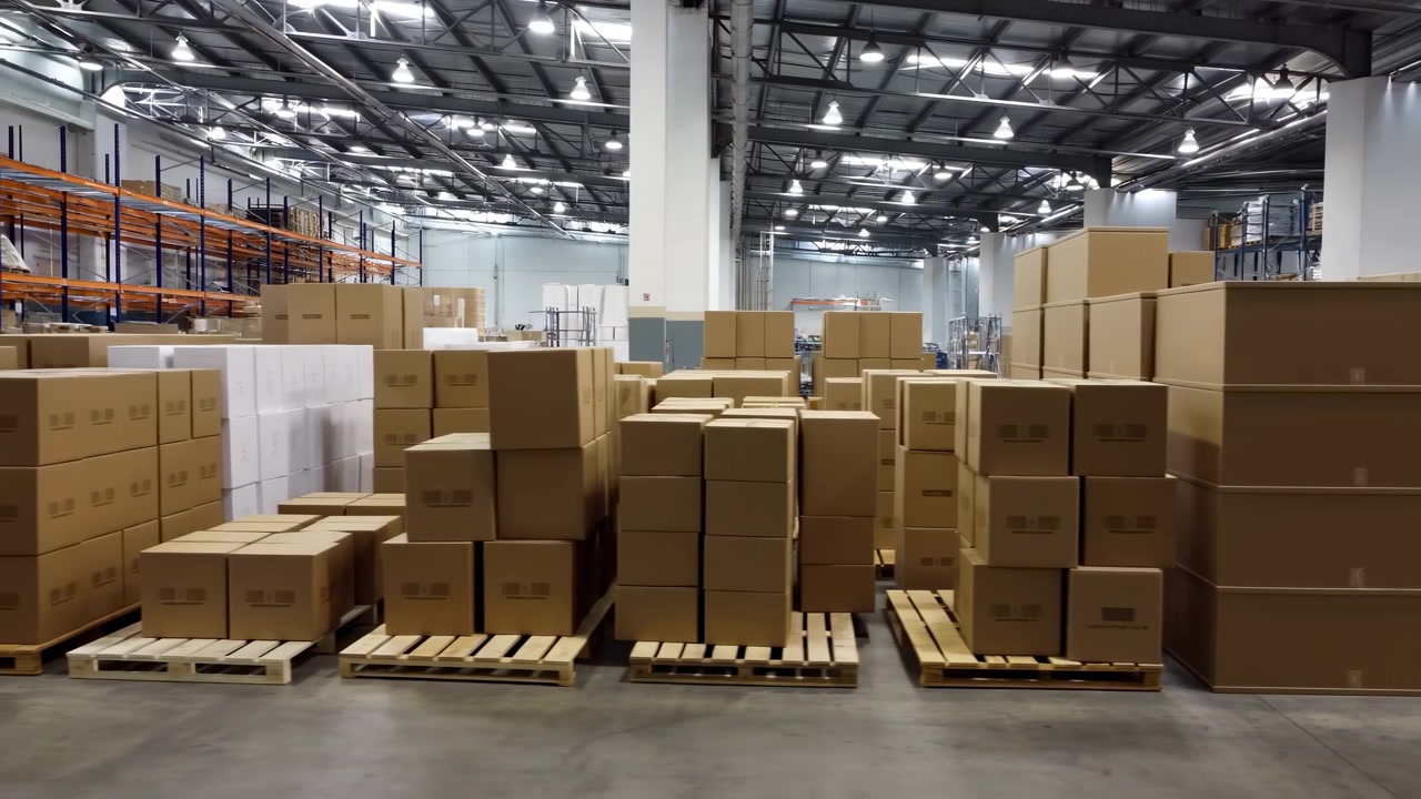 Magazzino con pallet e scatole impilati, grande centro di distribuzione con cartoni di cartone su pallet di legno.