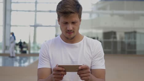 front view of smiling young man using smartphone.