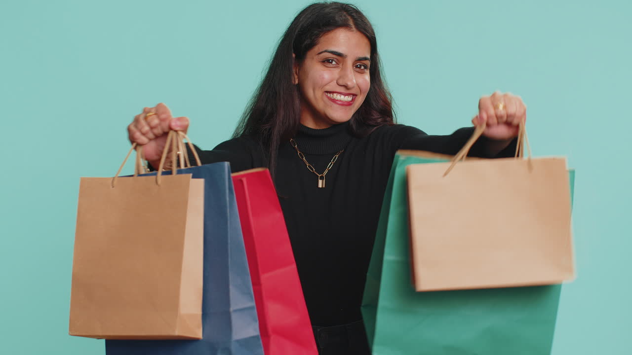 una mujer muestra con emoción sus bolsas de compras.
