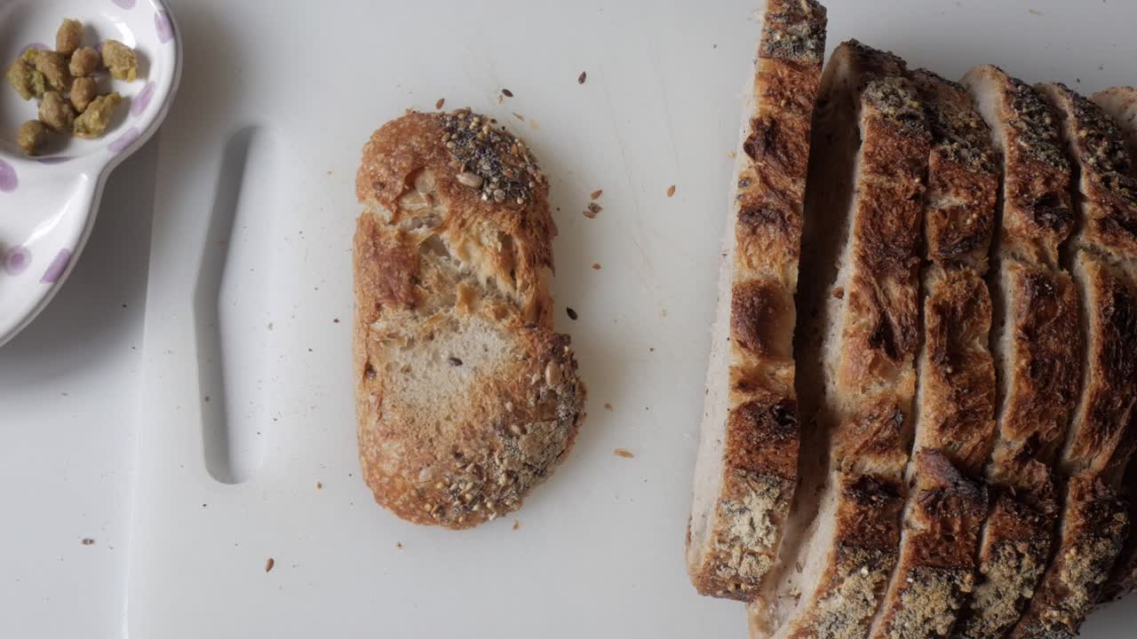 Freshly sliced olive bread on a clean surface with green olives in a dish