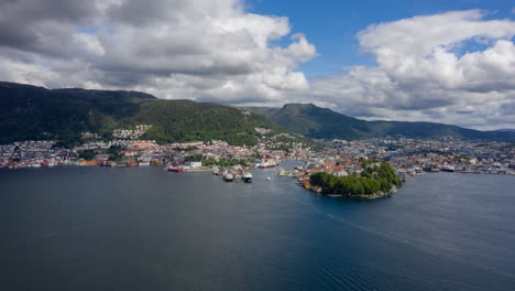 drone shot over the bay approaching bergen and bryggen on a sunny day with beautiful clouds