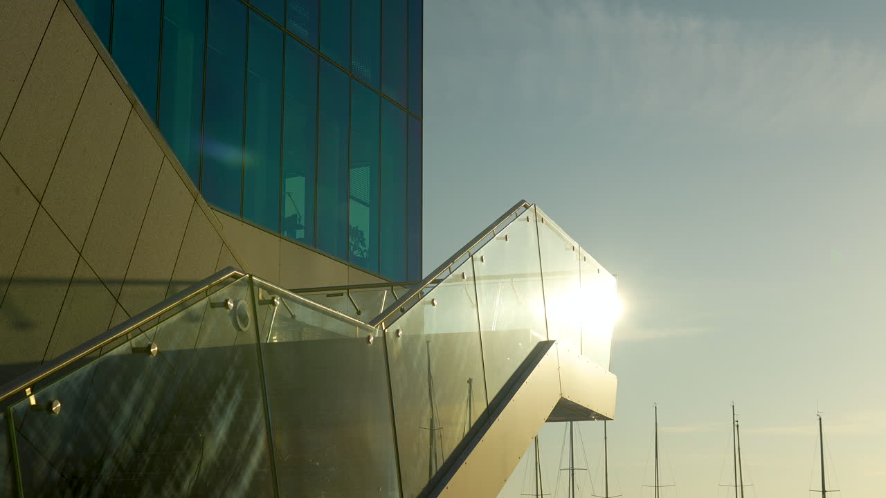 Edificio moderno de cristal con formas angulares al atardecer, reflejo y cielos despejados