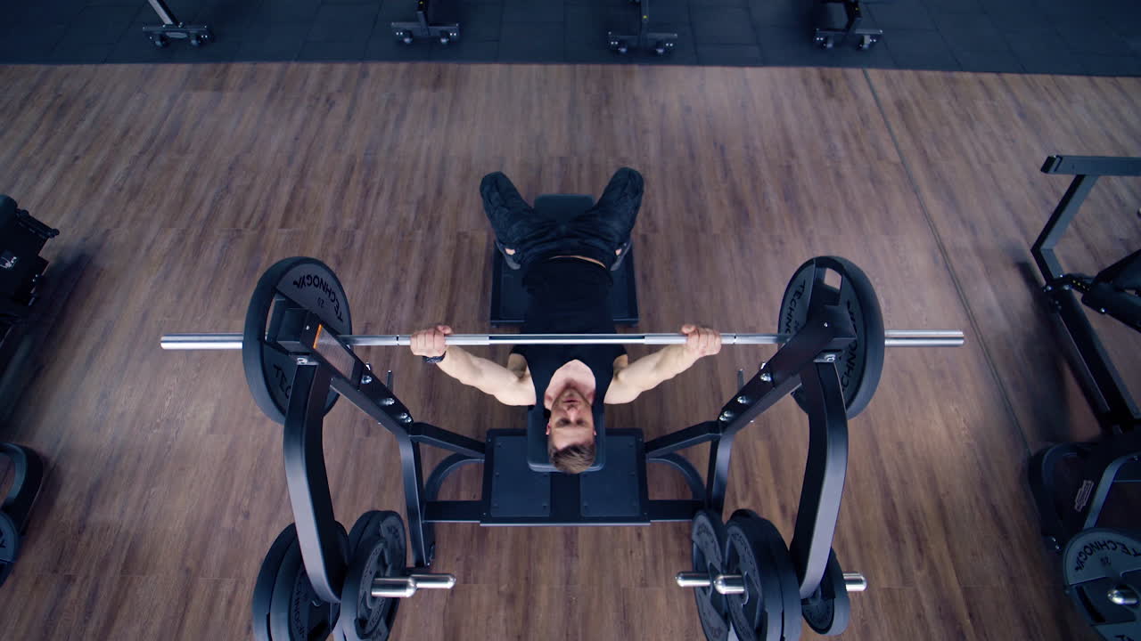 Athletic Bodybuilder Doing Barbell Exercise. Top view of professional athlete doing bench press workout with barbell