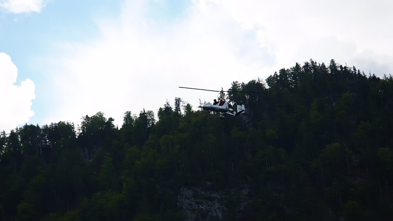 Gyroplane flying in the sky over lake Attersee, Austria.
