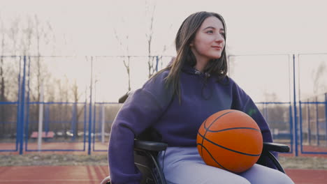 Mujer-Discapacitada-Girando-Las-Ruedas-De-Su-Silla-De-Ruedas-En-La-Cancha-De-Baloncesto-Mientras-Sostiene-Una-Pelota-De-Baloncesto