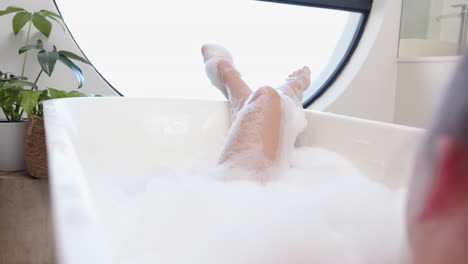 relaxing in bathtub, woman enjoying bubble bath with legs raised
